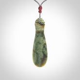 This is a sleek and slender hand carved New Zealand Jade mere pendant. The stone is a very beautiful green and the cord is either black, red or grey and is adjustable. The pendant has a light polish and just glows. Provided in a woven kete pouch.